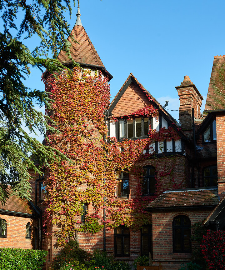 Careys Manor exterior with gravel driveway and red floral displays